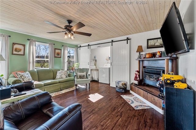 living room featuring wooden ceiling, dark hardwood / wood-style floors, a barn door, ceiling fan, and washer / dryer