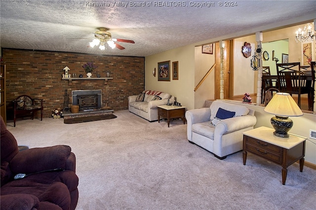 living room with a wood stove, ceiling fan, a textured ceiling, carpet floors, and brick wall