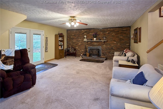 carpeted living room with a textured ceiling, a wood stove, and ceiling fan