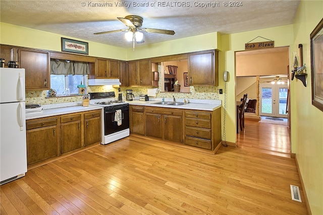 kitchen featuring white appliances, backsplash, sink, light hardwood / wood-style flooring, and a textured ceiling