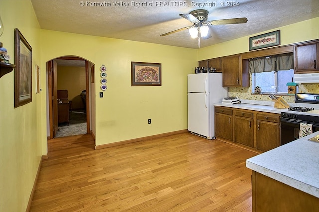 kitchen featuring light wood-type flooring, white appliances, a textured ceiling, and range hood