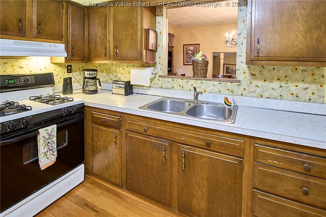 kitchen featuring a notable chandelier, white range with gas stovetop, sink, and light hardwood / wood-style flooring