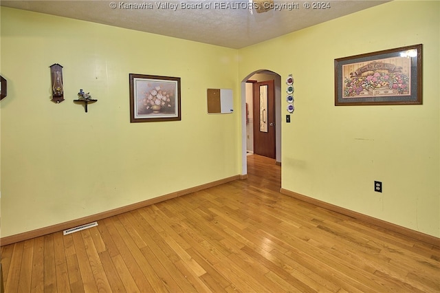 unfurnished room featuring a textured ceiling and light hardwood / wood-style floors