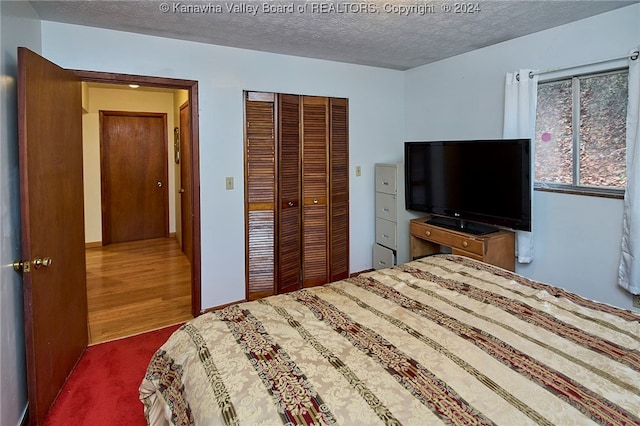 bedroom with a textured ceiling, a closet, and dark wood-type flooring