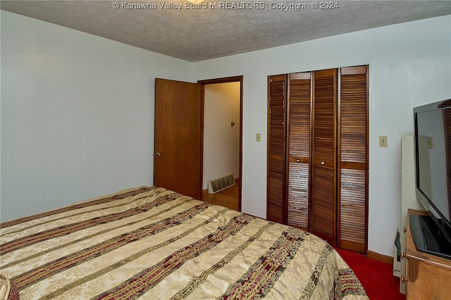 bedroom with a closet, a textured ceiling, and dark colored carpet