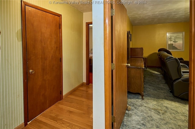 corridor with light hardwood / wood-style floors and a textured ceiling