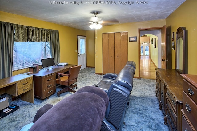 carpeted office space with ceiling fan and a textured ceiling