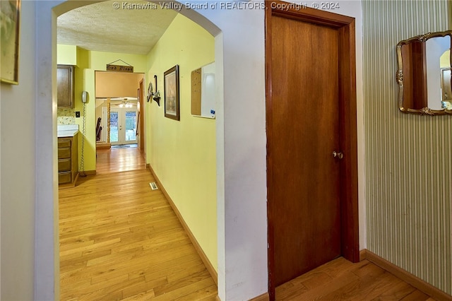 corridor featuring a textured ceiling and light hardwood / wood-style floors