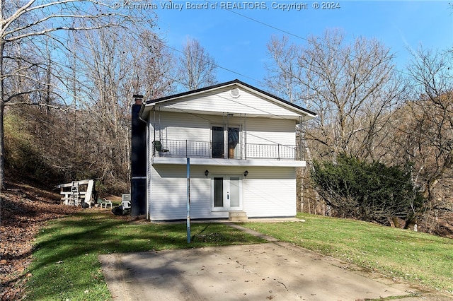 rear view of house featuring a yard and a balcony