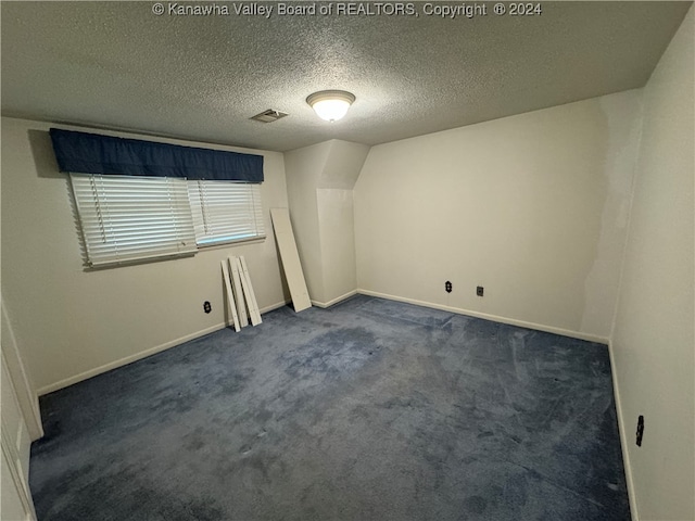 spare room with dark carpet and a textured ceiling