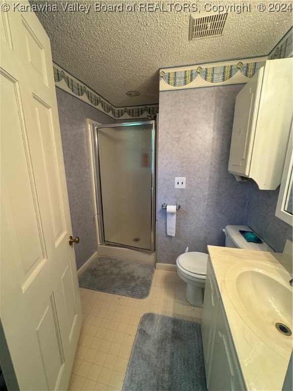 bathroom featuring vanity, a shower with shower door, a textured ceiling, and toilet