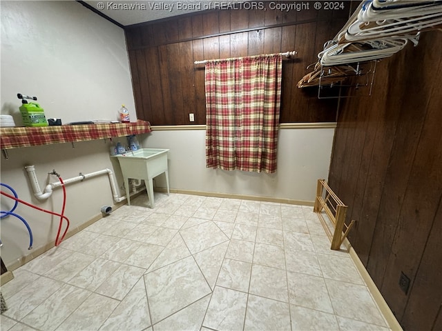 clothes washing area with wood walls and light tile patterned floors