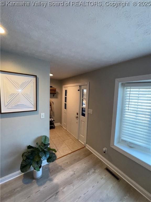 foyer with light wood-type flooring and a textured ceiling