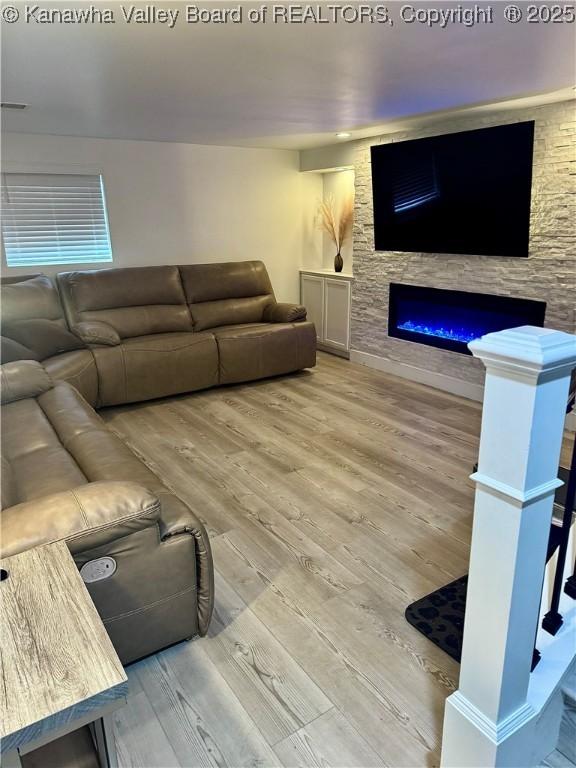 living room featuring hardwood / wood-style flooring and a stone fireplace