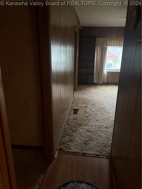 hall with carpet and wood walls