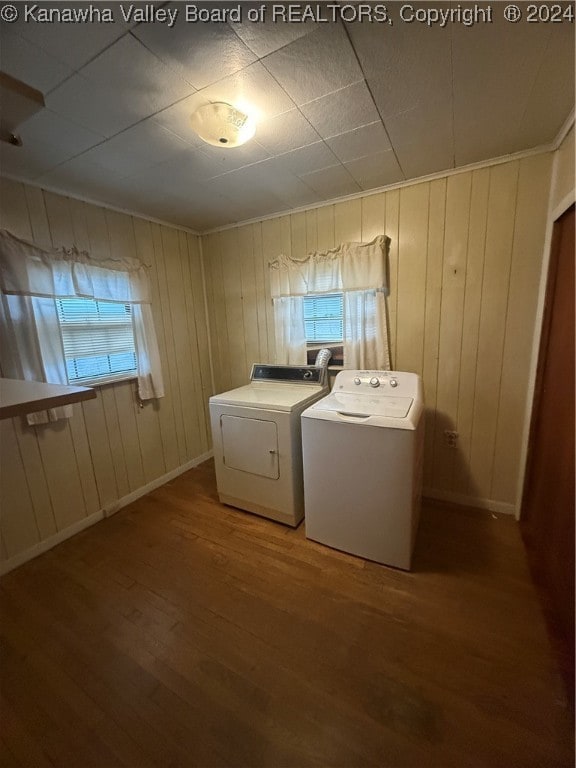 washroom featuring hardwood / wood-style flooring, wood walls, and washing machine and clothes dryer