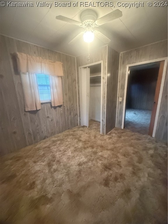 unfurnished bedroom featuring ceiling fan and wooden walls