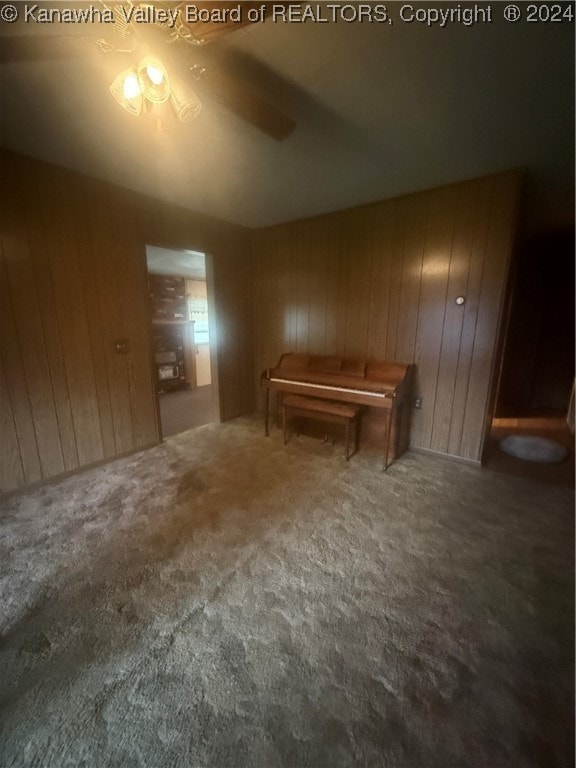 interior space with wood walls, carpet, and ceiling fan