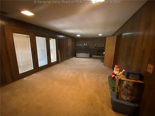 basement with black refrigerator, light carpet, wooden walls, and french doors