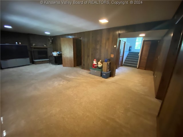 basement featuring wooden walls and light colored carpet