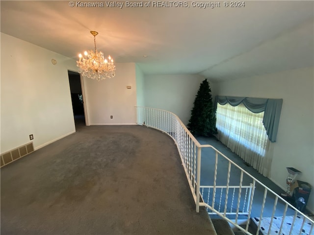 carpeted empty room with an inviting chandelier and lofted ceiling