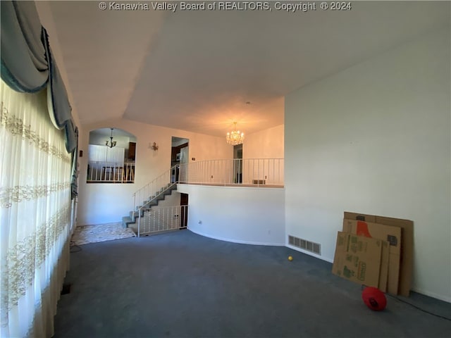 unfurnished living room with dark colored carpet, vaulted ceiling, and an inviting chandelier