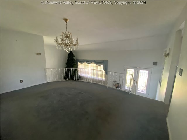 carpeted empty room featuring a towering ceiling and a notable chandelier