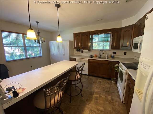 kitchen with dark brown cabinets, white appliances, sink, pendant lighting, and a chandelier