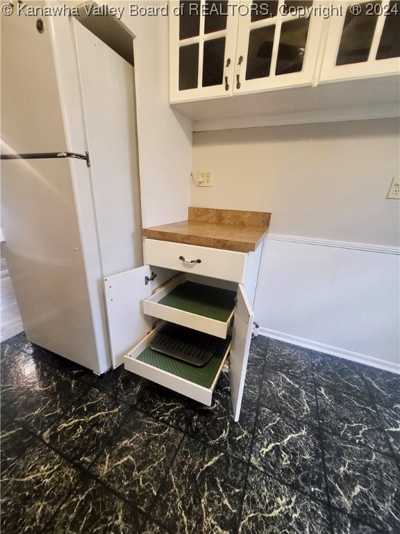 interior details featuring butcher block countertops, white refrigerator, and white cabinets