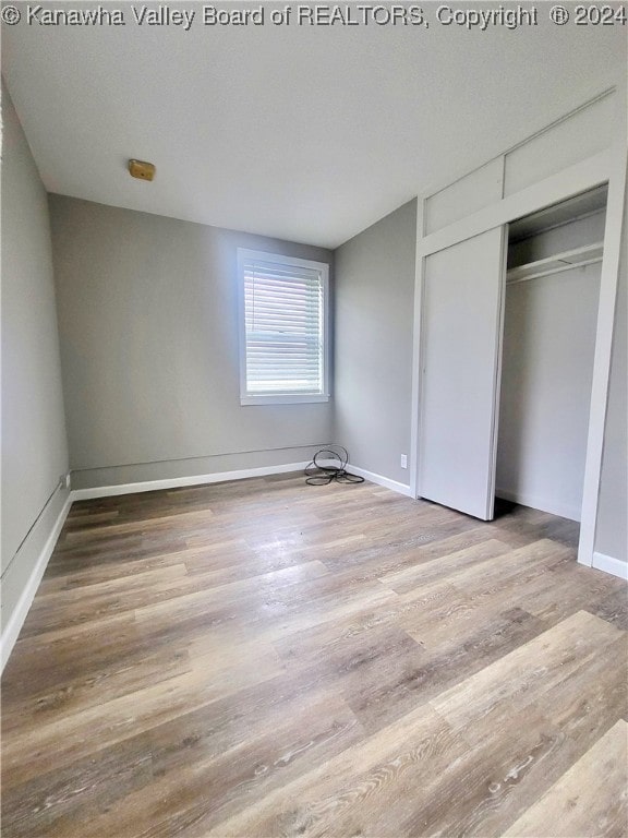 unfurnished bedroom with hardwood / wood-style floors and a closet