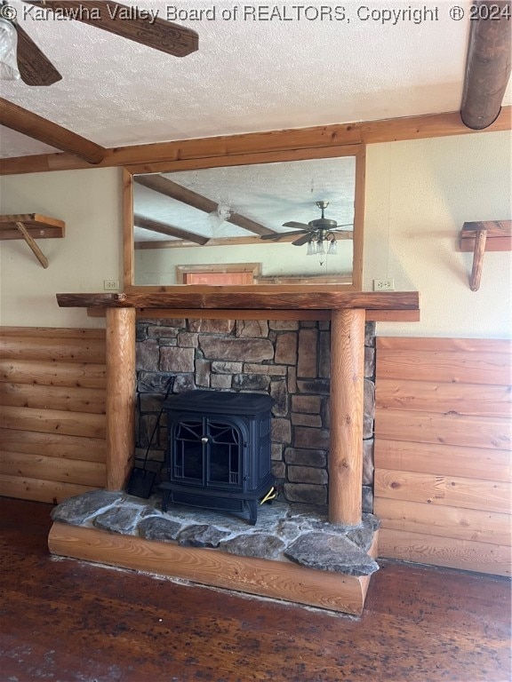 room details featuring beam ceiling, a wood stove, hardwood / wood-style floors, and a textured ceiling