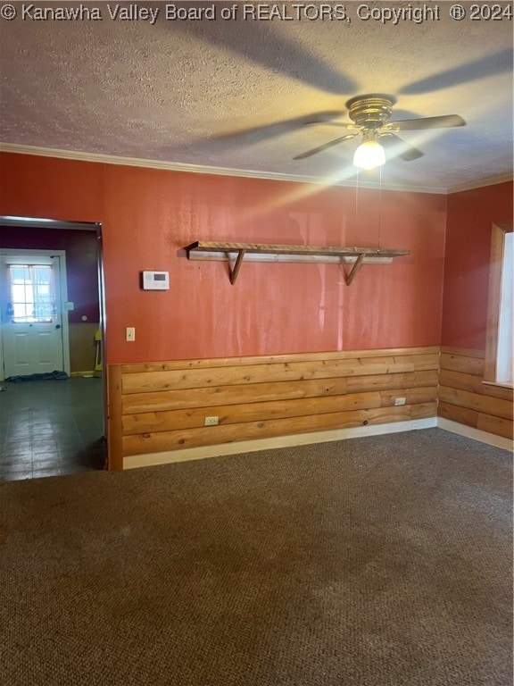 carpeted empty room with ceiling fan, ornamental molding, and a textured ceiling