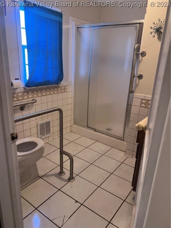 bathroom with tile patterned flooring, toilet, tile walls, and walk in shower