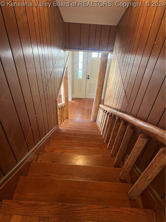 staircase featuring hardwood / wood-style floors and wood walls