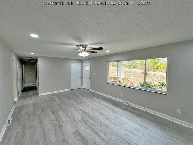 empty room featuring a textured ceiling, light hardwood / wood-style floors, and ceiling fan