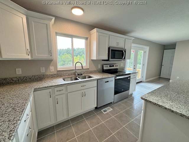 kitchen with white cabinetry, sink, stainless steel appliances, and light stone counters