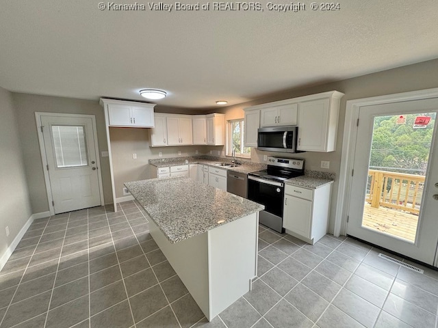 kitchen with white cabinets, a center island, stainless steel appliances, and a wealth of natural light