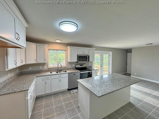 kitchen featuring stainless steel appliances, white cabinetry, and plenty of natural light