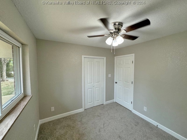 unfurnished bedroom with ceiling fan, a closet, light carpet, and a textured ceiling