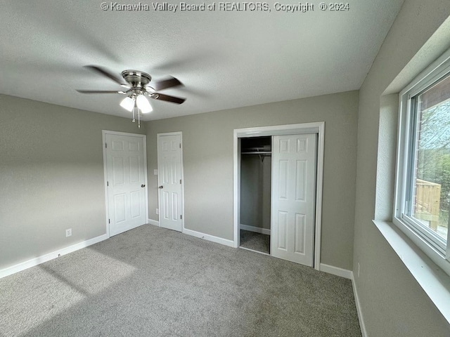 unfurnished bedroom with multiple closets, ceiling fan, carpet floors, and a textured ceiling