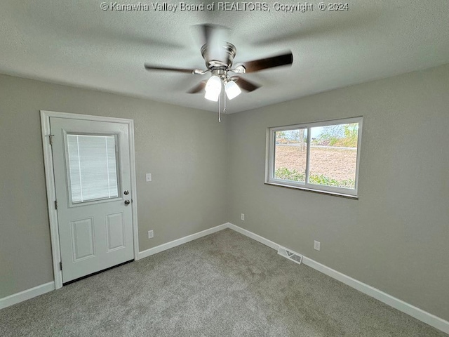 spare room featuring a textured ceiling, light colored carpet, and ceiling fan