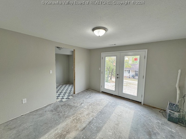 empty room featuring french doors and a textured ceiling