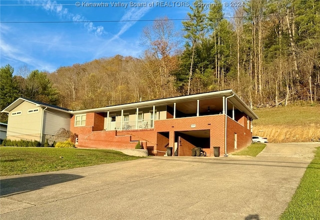 view of front of house featuring a carport, covered porch, and a front lawn