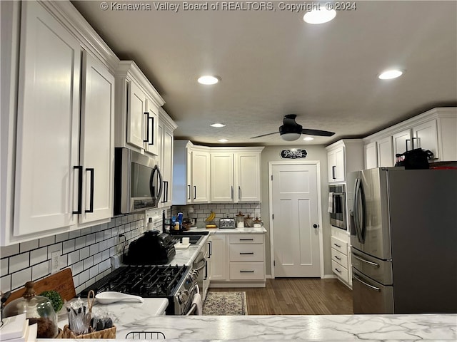 kitchen with appliances with stainless steel finishes, tasteful backsplash, white cabinetry, and dark wood-type flooring