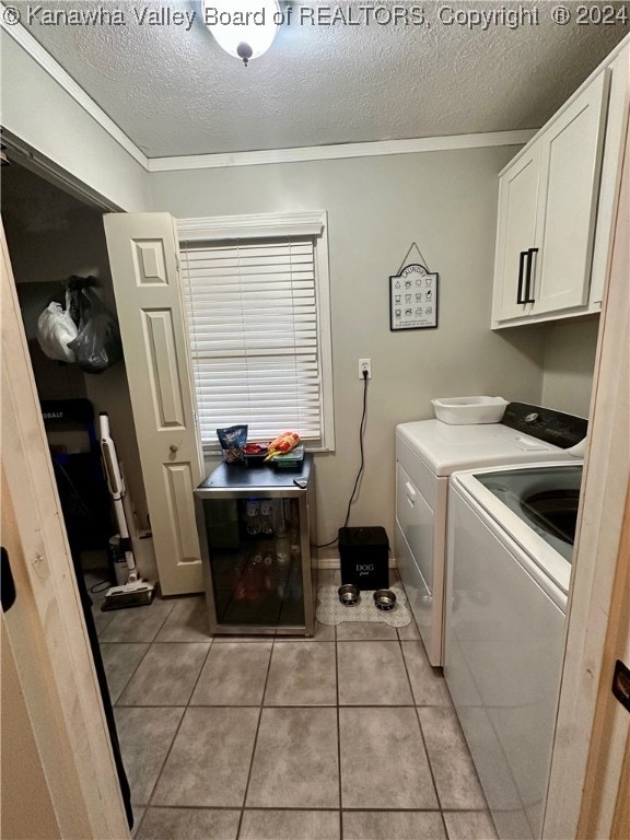 laundry area with cabinets, light tile patterned floors, a textured ceiling, and washing machine and clothes dryer