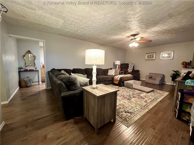 living room with ceiling fan, dark hardwood / wood-style flooring, and a textured ceiling