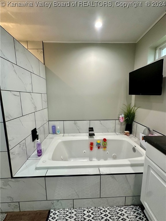 bathroom featuring vanity and a relaxing tiled tub