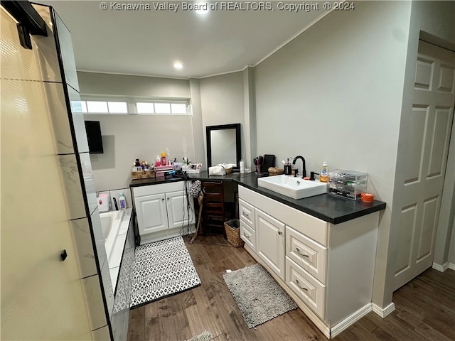 bathroom with a washtub, hardwood / wood-style floors, and vanity