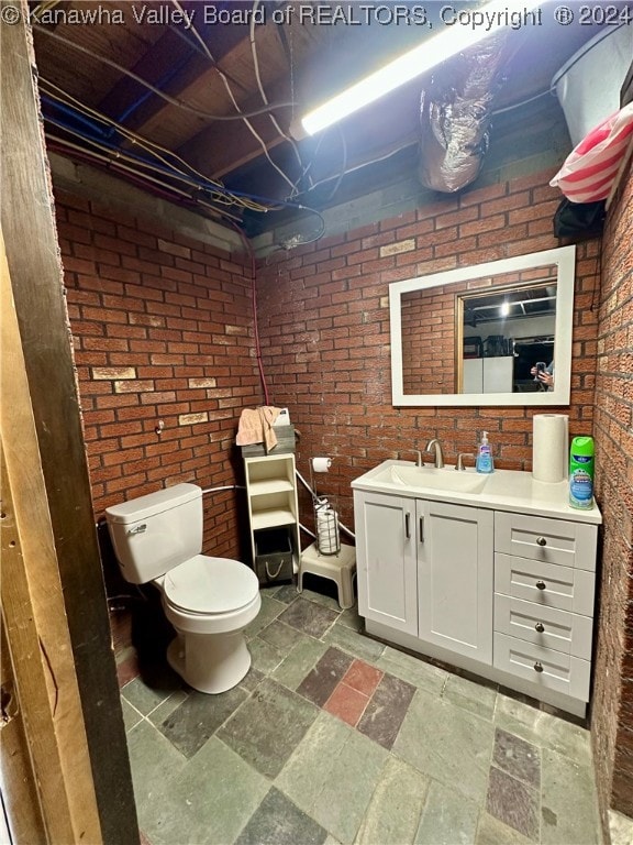 bathroom with vanity, brick wall, and toilet