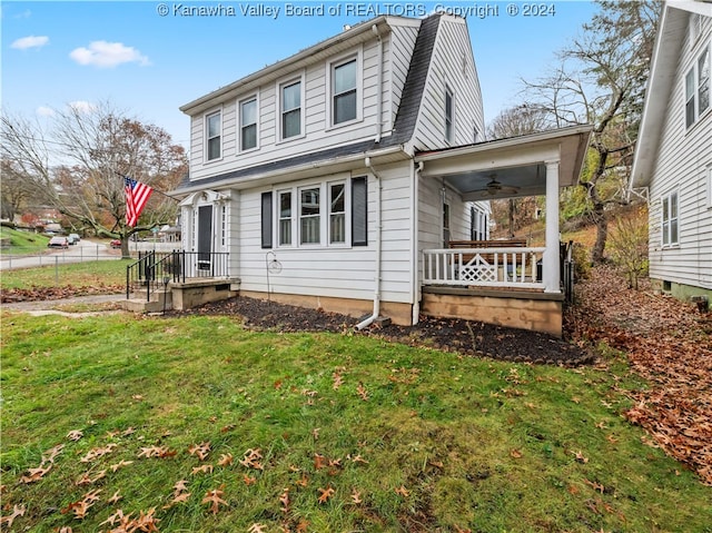 view of front of house featuring ceiling fan, covered porch, and a front yard